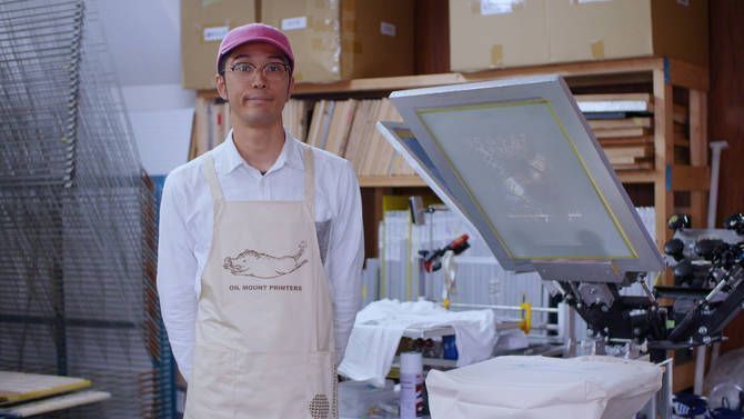 印刷機の前に立つ日高さん