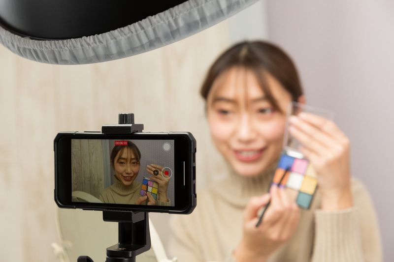 メイクアップ動画らしきものをスマホで自撮り撮影する若い女性