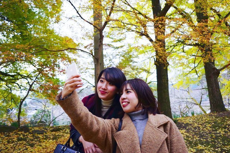 秋月の紅葉と自撮りを楽しむ女性