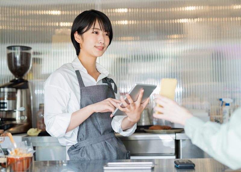 カフェ スタッフにスマートフォンを見せる女性