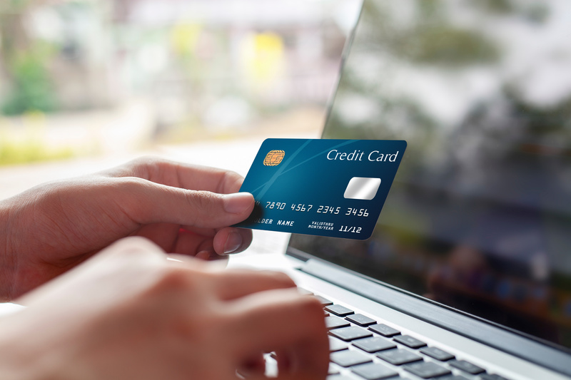 クレジットカードを持ちながらパソコンを操作