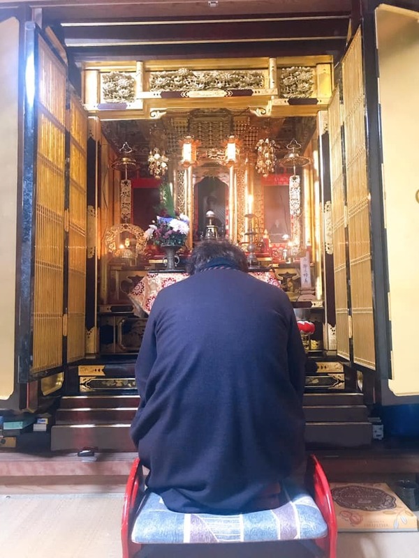 仏壇の前に座る男性